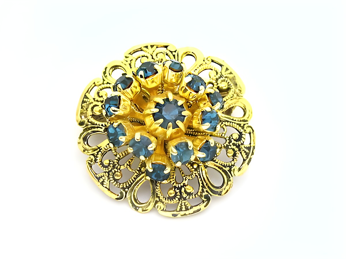 Damen Brosche im Sexy City Look in Blau, rund, hergestellt von Juwelier Harnisch, mit funkelnden Strasssteinen in blauer Farbe und filigranem goldfarbenem Design.