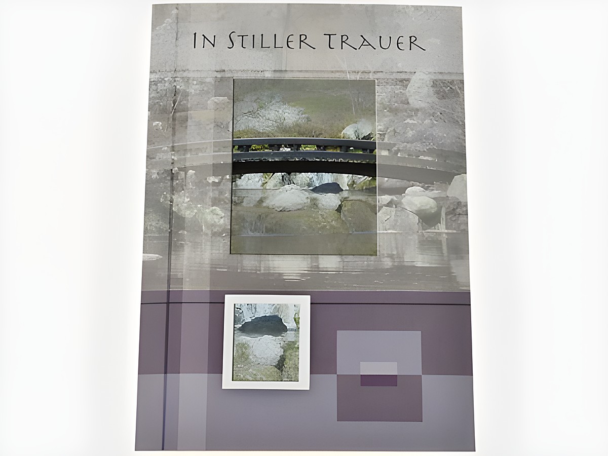 Eine Trauerkarte mit dem Text In stiller Trauer, abgebildet mit einer Szene von einer Brücke über ruhiges Wasser und Steinen, in sanften, dezenten Farben gestaltet, hergestellt von Juwelier Harnisch.