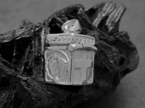 Eine silberne Truhe mit einem Kreuz, Füßchen und Herz-Motiv, die als Medaillon dient. Der Hersteller ist Juwelier Harnisch und es handelt sich um Sonderformen in Sterling Silber.