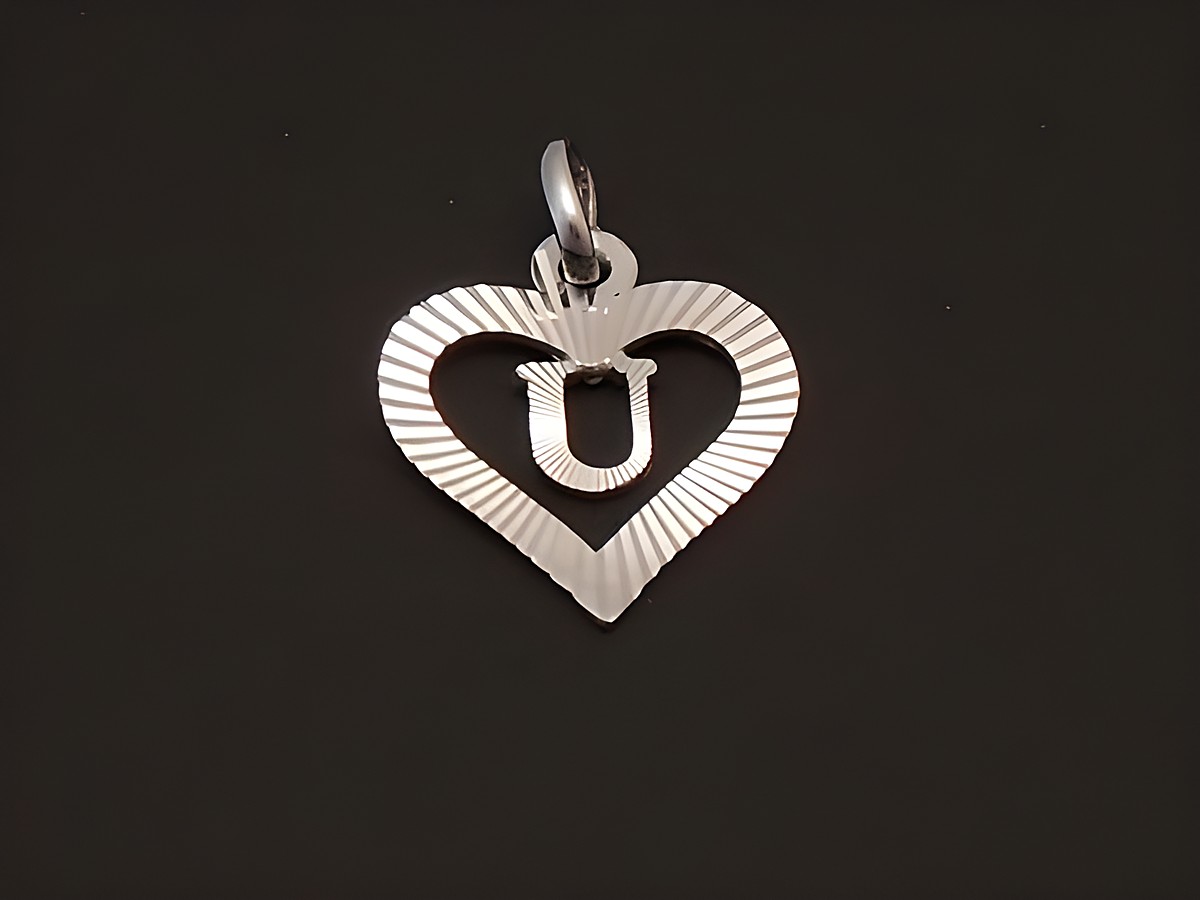 Herzförmiger Anhänger aus rhodiniertem Sterling Silber mit eingearbeitetem Buchstaben U, Hersteller Juwelier Harnisch, auf schwarzem Hintergrund präsentiert.