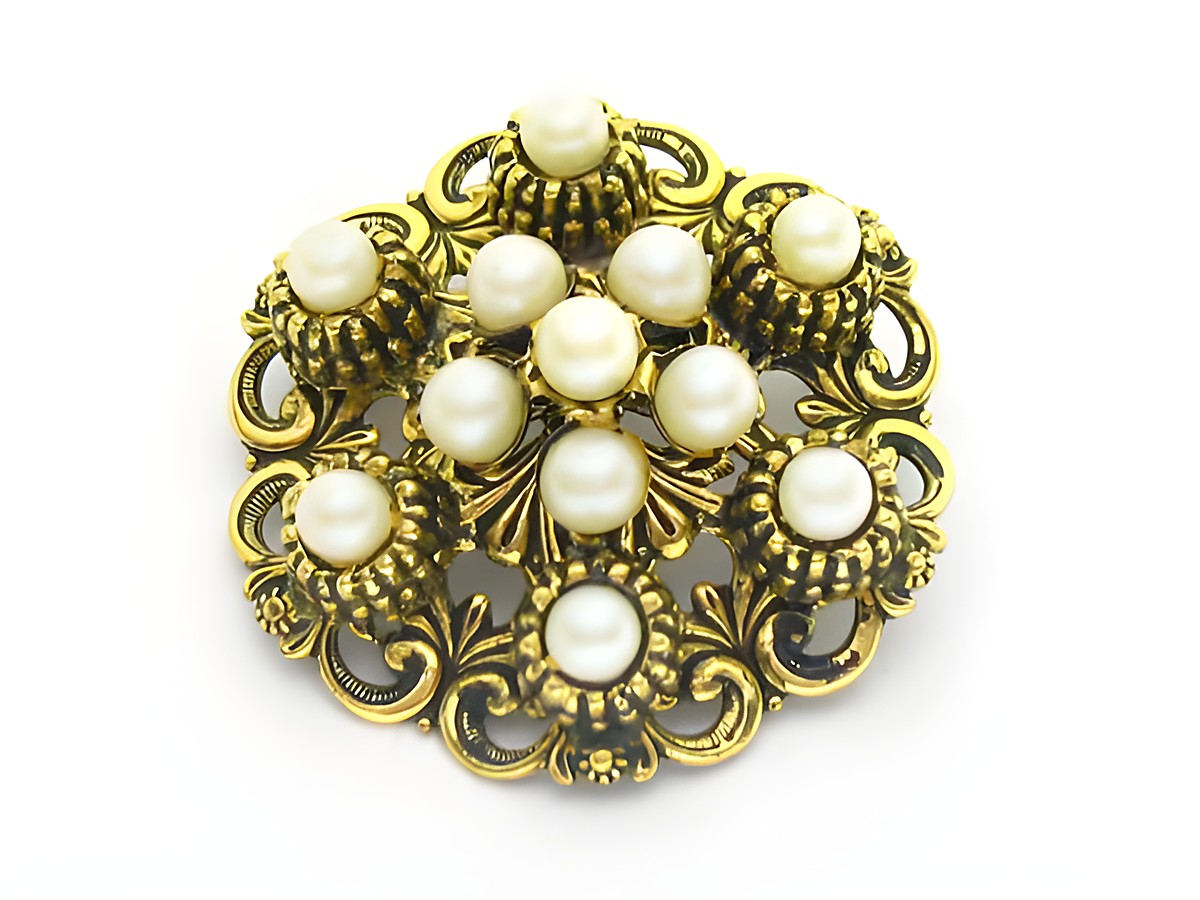 Die Brosche im Sexy City Look besteht aus goldfarbenem Metall mit Zuchtperl Imitationen, die in einer eleganten Anordnung platziert sind, idealer Modeschmuck von Juwelier Harnisch.