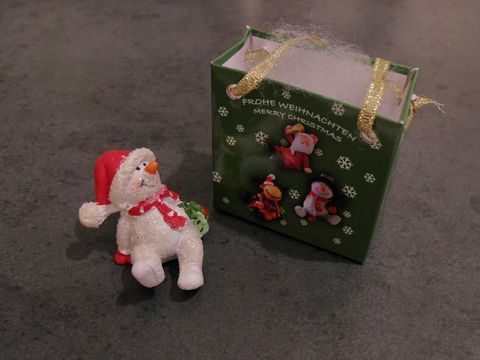 95105-0 Schneemann mit Geschenktasche sitzend mit Geschenk von Juwelier Harnisch zu Weihnachten.