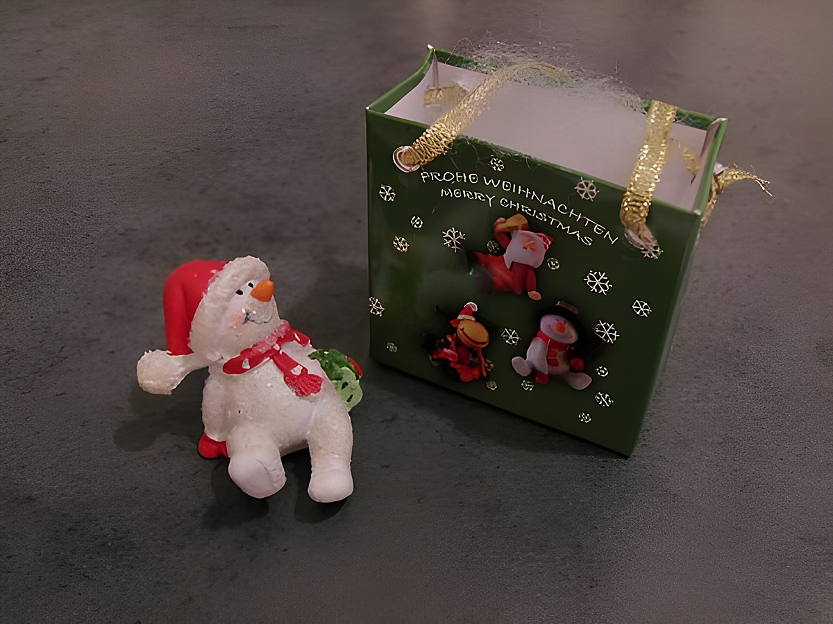Schneemann mit Geschenktasche sitzend mit Geschenk von Juwelier Harnisch zu Weihnachten.