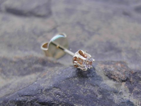 Einohrstecker unisex aus Gold 585 mit funkelndem Zirkonia, Hersteller Juwelier Harnisch, Einzelstück auf einem grauen Untergrund präsentiert.