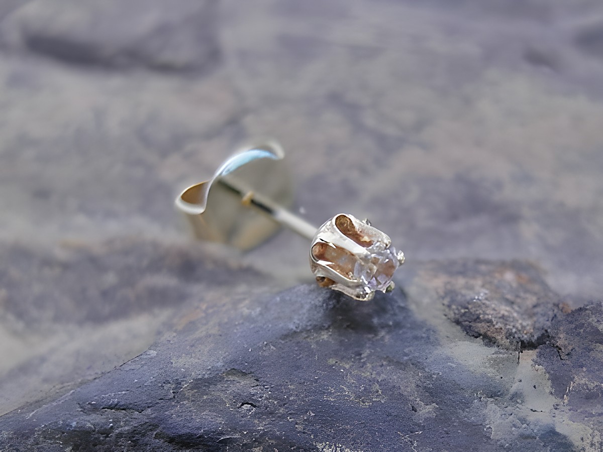Einohrstecker unisex aus Gold 585 mit funkelndem Zirkonia, Hersteller Juwelier Harnisch, Einzelstück auf einem grauen Untergrund präsentiert.