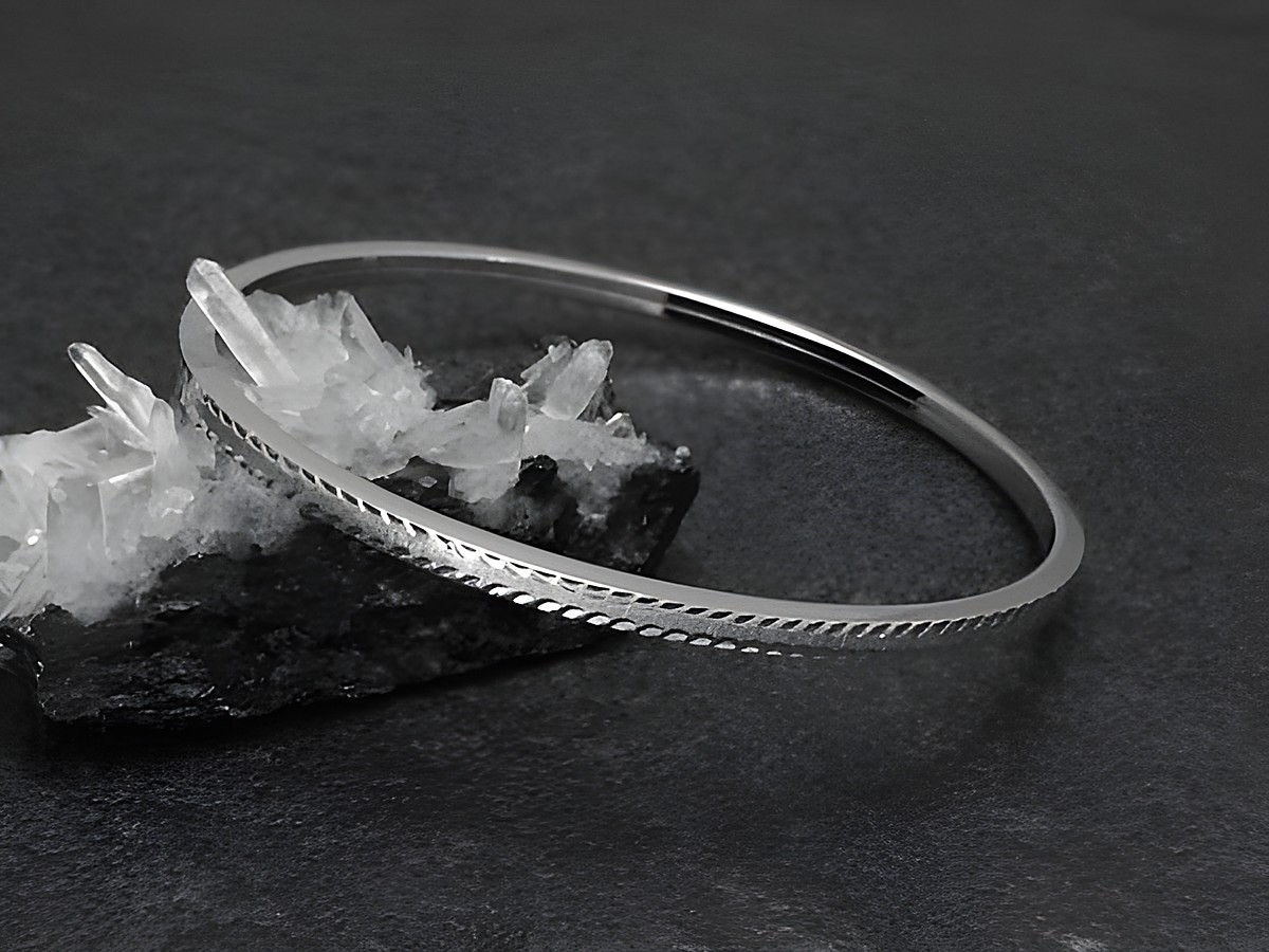 Silber Armreifen aufregend 3 mm rhodiniert 18 cm vom Hersteller Juwelier Harnisch auf schwarzem Untergrund neben kristallähnlichen Steinen platziert. Elegantes Design für modebewusste Trägerinnen.