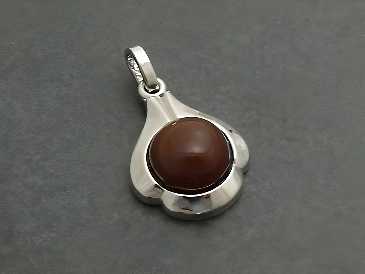 Eleganter Tropfen-Anhänger aus rhodiniertem Silber mit einem runden Karneol in der Mitte, gefertigt vom Juwelier Harnisch. Ideal für stilvolle Akzente.