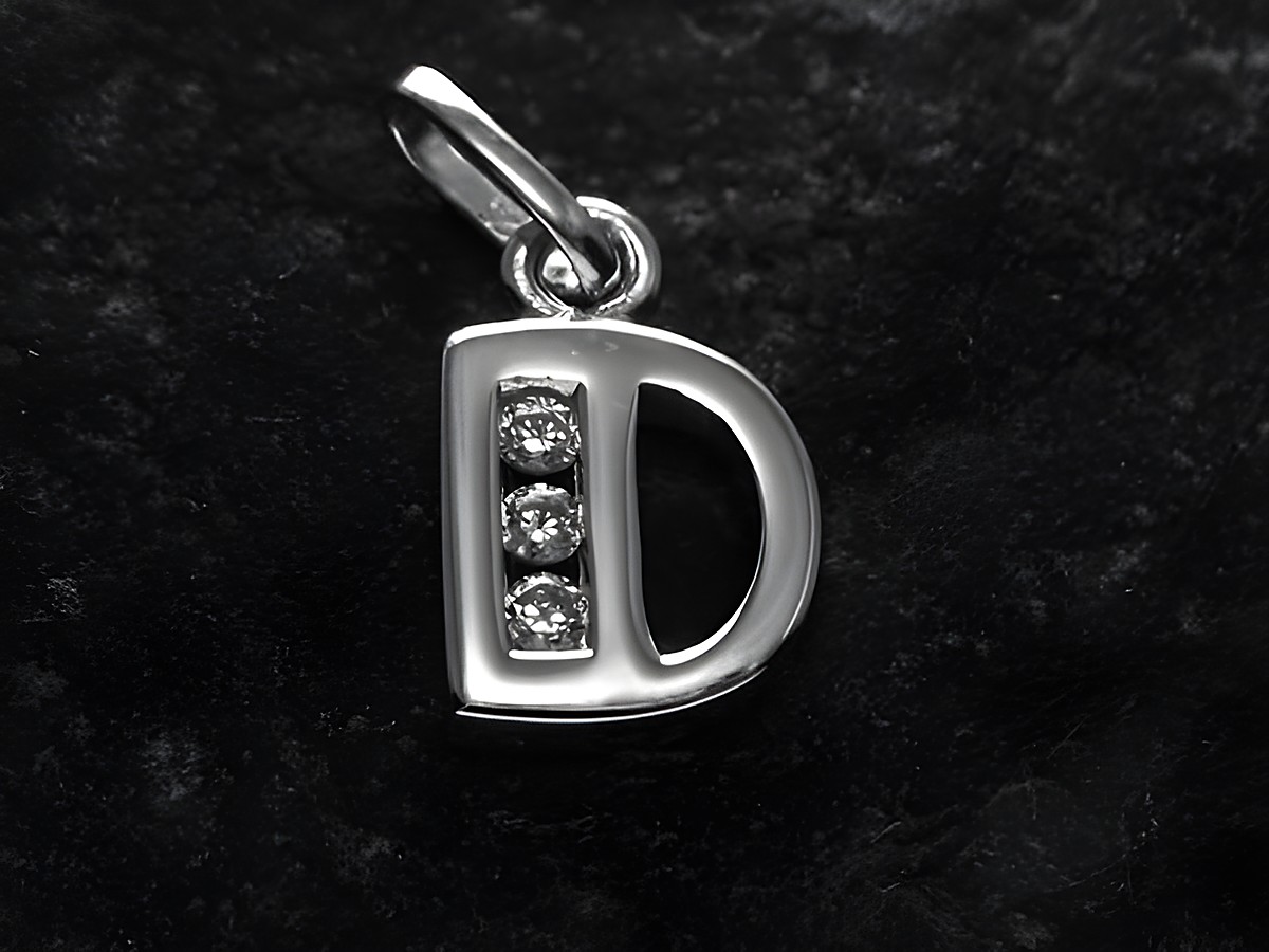 Anhänger aus Silber rhodiniert in Form des Buchstabens D, verziert mit drei Zirkonia, Hersteller Juwelier Harnisch.