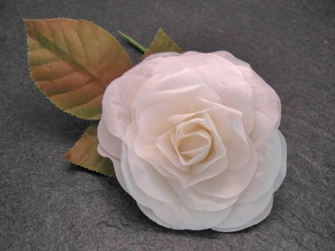 Haarschmuck mit einer opulenten, weißen Rose aus Textil und Blättern, ideal als Brosche von Juwelier Harnisch, verleiht eleganten Akzent und feierlichen Charme.