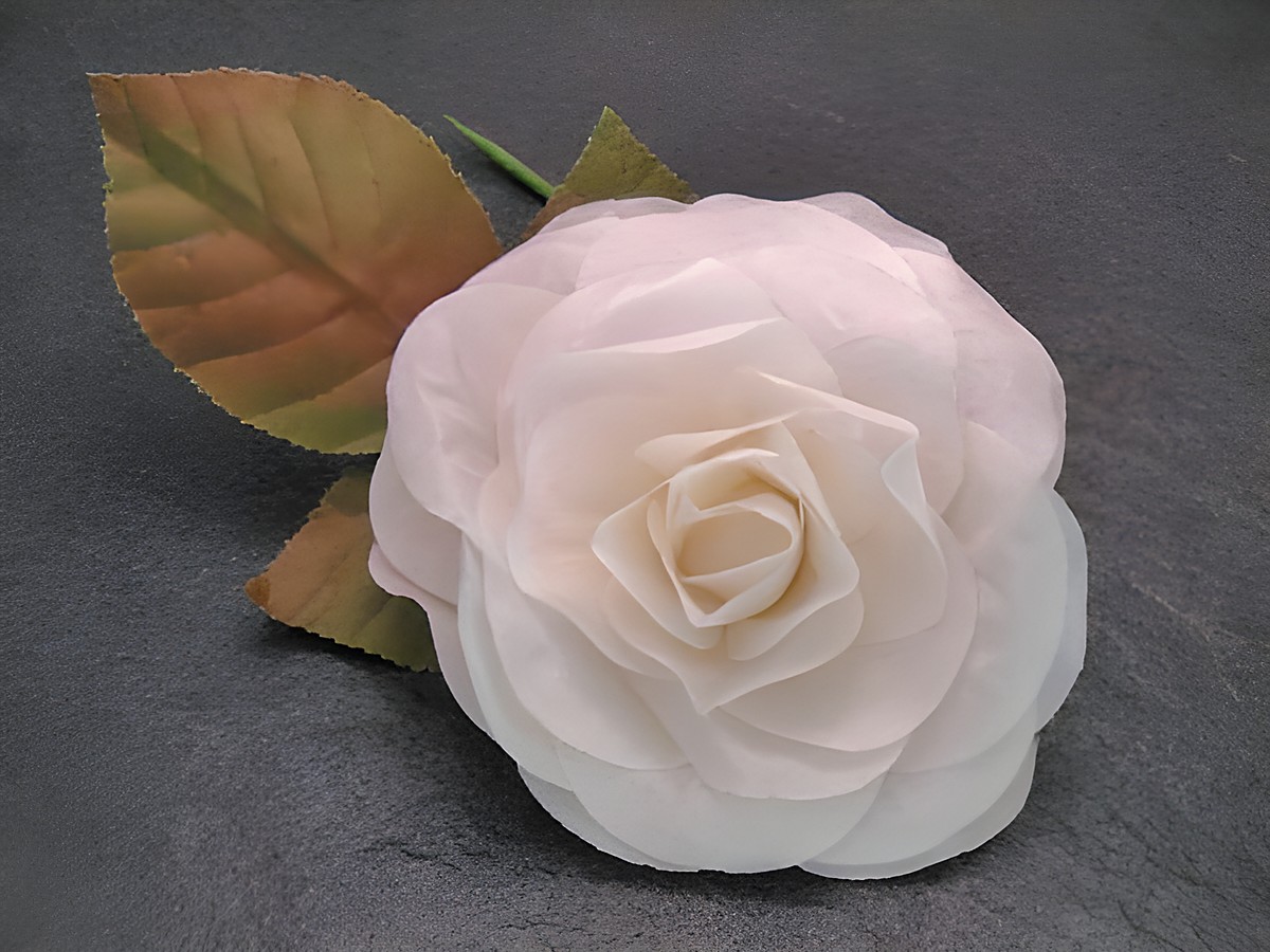 Haarschmuck mit einer opulenten, weißen Rose aus Textil und Blättern, ideal als Brosche von Juwelier Harnisch, verleiht eleganten Akzent und feierlichen Charme.