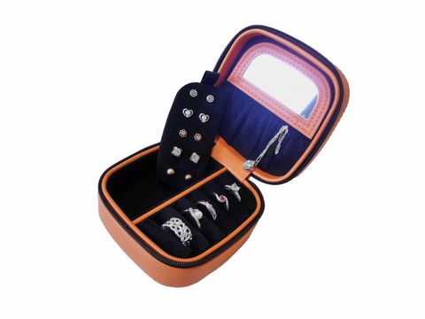 Schmuckkästchen in Orange mit einem schmalen Tragegriff, geöffnet und gefüllt mit verschiedenen Schmuckstücken wie Ringen und Ohrsteckern, hergestellt von Juwelier Harnisch, Maße 10 cm.