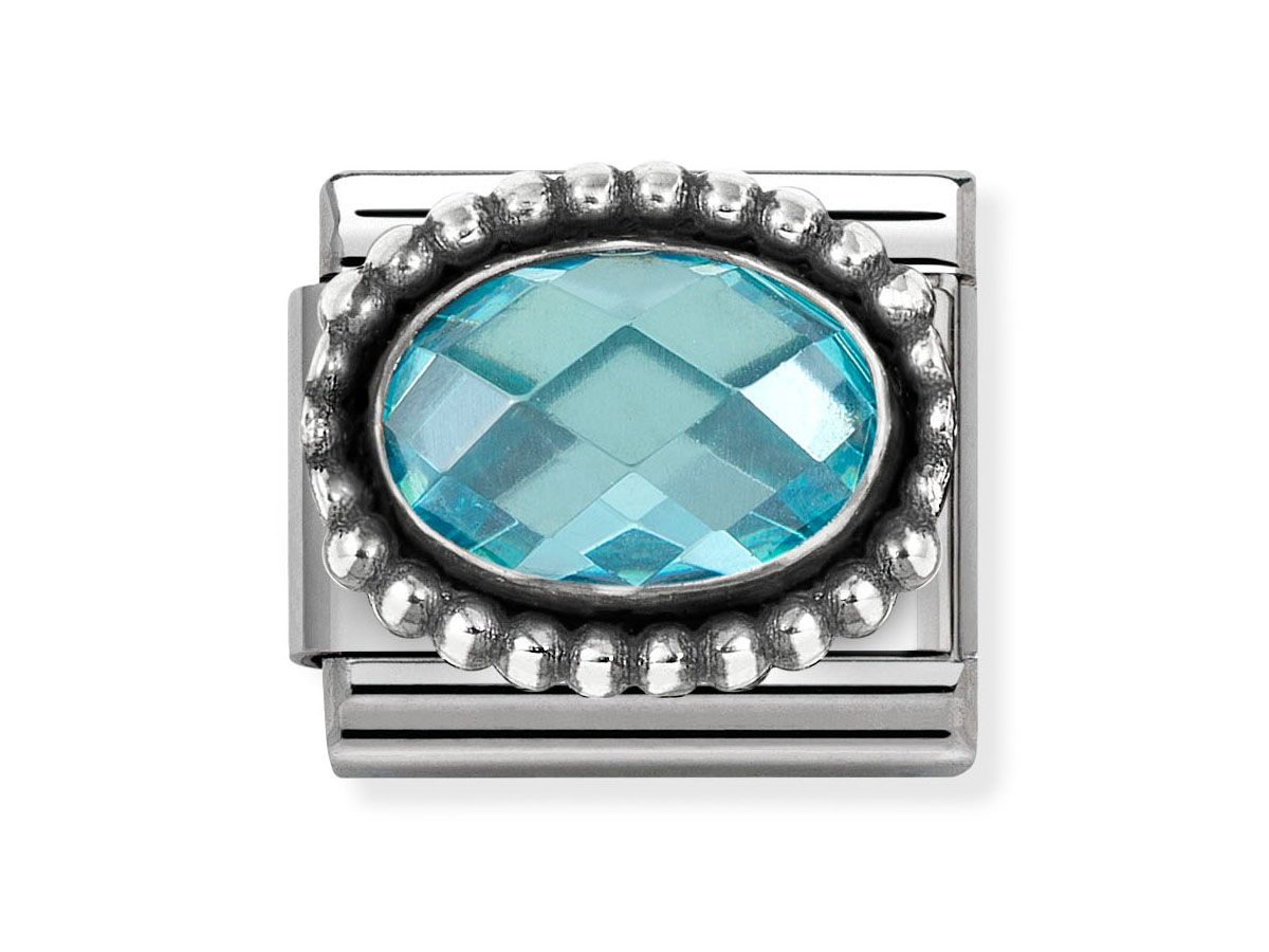 Ein ovaler, himmelblauer Zirkonia mit facettiertem Schliff, umgeben von einer gezackten Silberfassung aus Sterlingsilber, Teil eines eleganten Schmuckstücks von Nomination.