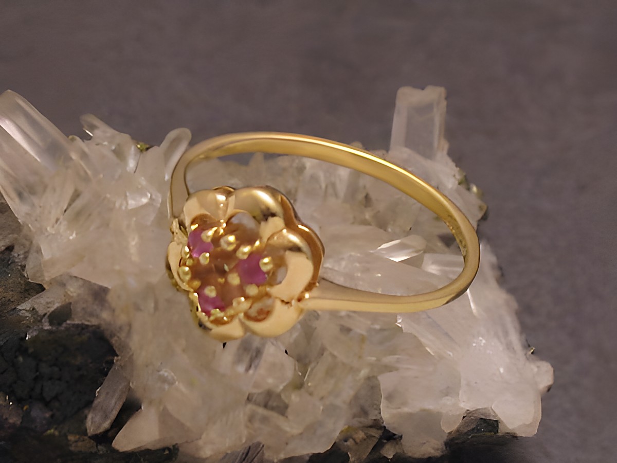 Goldring in lieblicher Blütenform aus Gold 333 mit Rubinbesatz, Größe 57, Hersteller Juwelier Harnisch, bis Größe 58/18,5, auf kristallinem Hintergrund präsentiert.