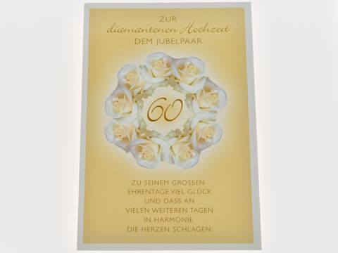 Hochzeitskarte zur diamantenen Hochzeit mit einem Kranz aus weißen Rosen auf goldenem Hintergrund, mit dem Text zu Glückwünschen für das Jubelpaar. Hersteller: Juwelier Harnisch.