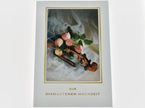 Eine elegante Hochzeitskarte mit Rosen, einer Violine und Notenpapier, gestaltet von Juwelier Harnisch, für die diamantene Hochzeit. Die Karte vermittelt festliche Stimmung.