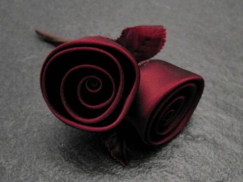 Zwei bordeauxrote Satinrosen in stilvoller Form, ideal als Haarschmuck oder Brosche, hergestellt von Juwelier Harnisch, perfekt für traumhafte Anlässe.