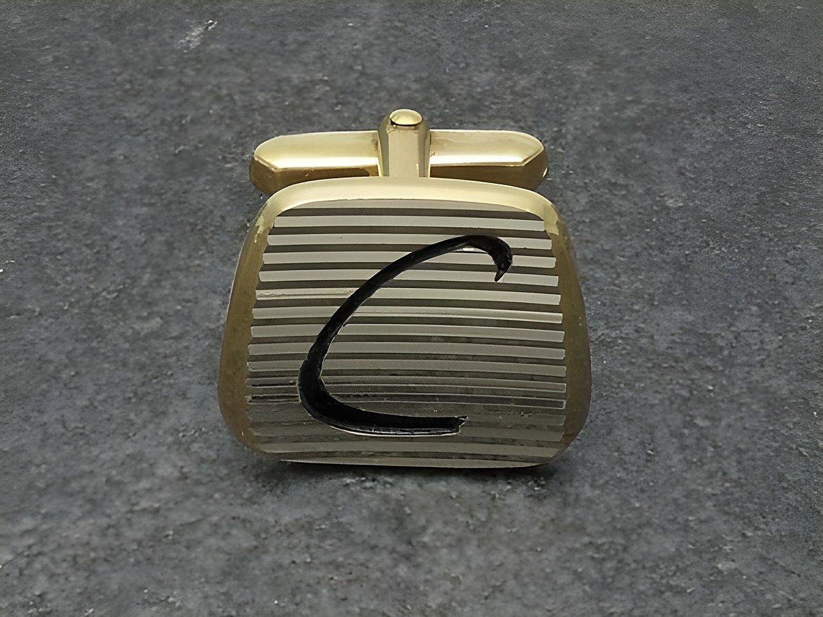Vergoldete Manschettenknöpfe mit Initialen C, Hersteller Juwelier Harnisch, elegante Gestaltung mit feinen Rillen und schwarzem Buchstaben C. Ideal für stilvolle Anlässe.
