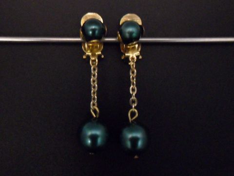 Ohrclip in türkisgrün glänzend und zeitlos, ergänzt durch goldfarbene Elemente aus Kunstharz. Hersteller: Juwelier Harnisch, Vorlage für eleganten Schmuck.