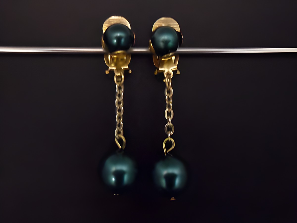 Ohrclip in türkisgrün glänzend und zeitlos, ergänzt durch goldfarbene Elemente aus Kunstharz. Hersteller: Juwelier Harnisch, Vorlage für eleganten Schmuck.