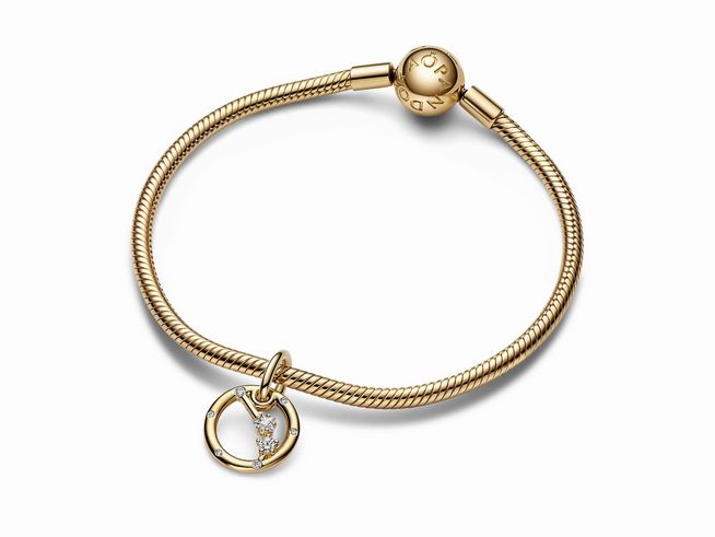 Eine elegante Armbanduhr mit einem vergoldeten Armband und einem charm Anhänger in Form des Sternzeichens Widder, verziert mit Zirkonia. Ideal für astrologische Schmuckliebhaber.