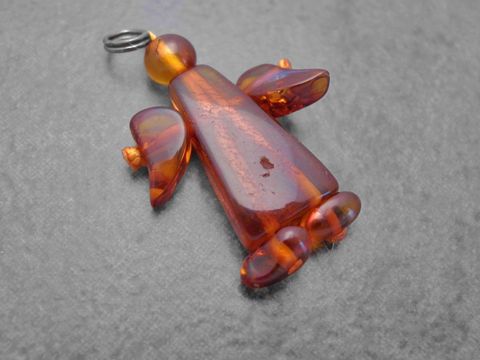Engel Anhänger aus braunem Bernstein von Juwelier Harnisch, schützend gestaltet mit geschwungenen Flügeln und detailreicher Form, ideal als schöner Schmuck oder Geschenk.