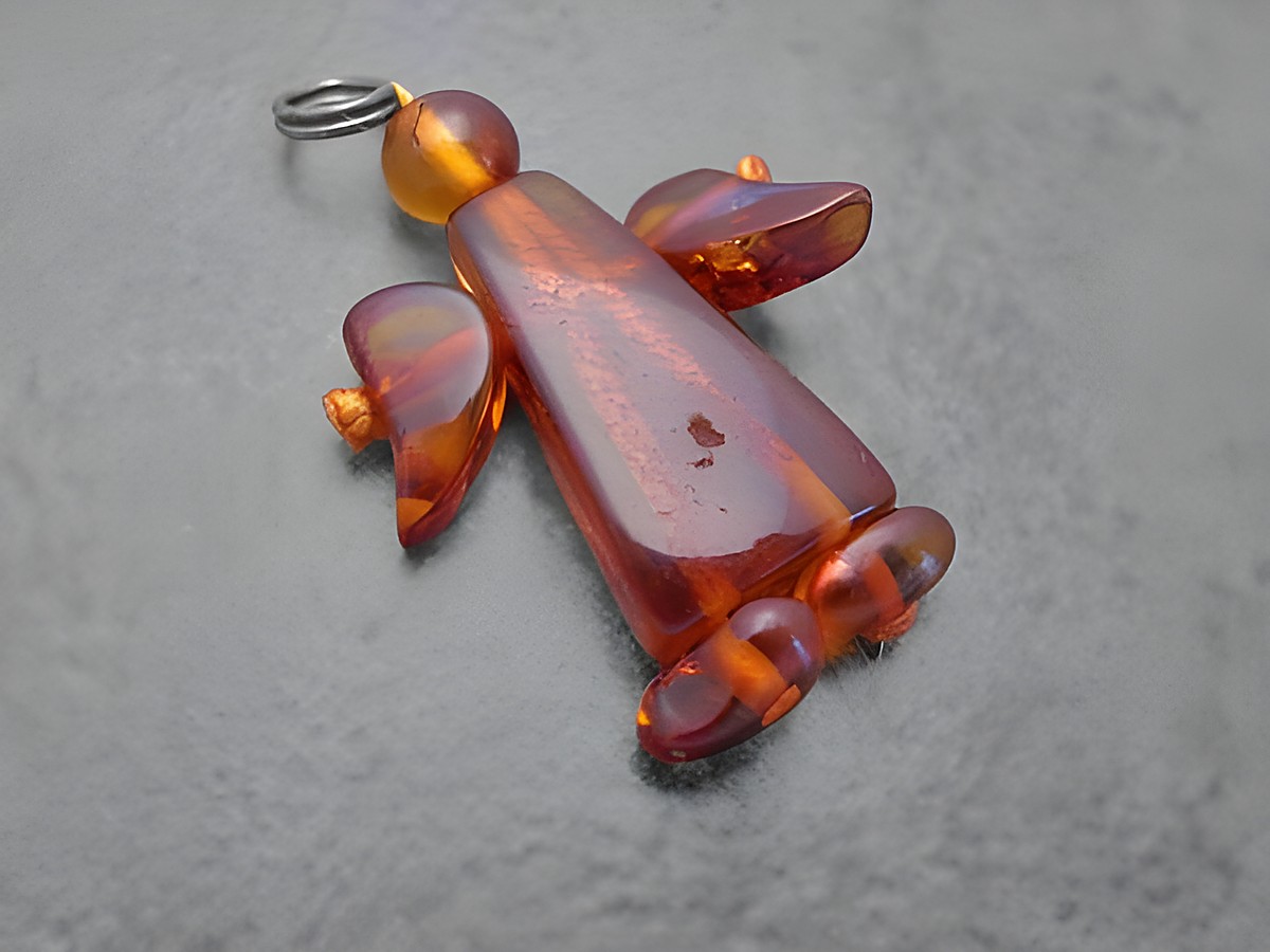 Engel Anhänger aus braunem Bernstein von Juwelier Harnisch, schützend gestaltet mit geschwungenen Flügeln und detailreicher Form, ideal als schöner Schmuck oder Geschenk.