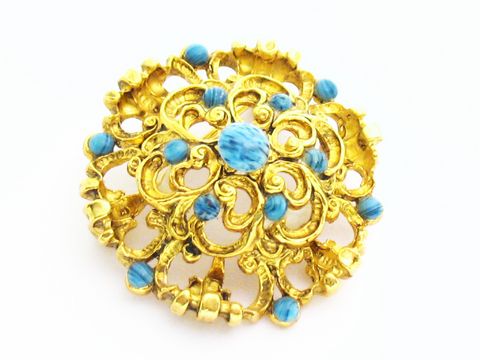 Damen Brosche im Sexy City Look in Blau rund, Hersteller Juwelier Harnisch, mit türkisen Akzenten und filigranem goldfarbenem Design, idealer Schmuck für jeden Anlass.