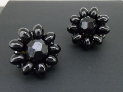 Ohrclip in schwarz mit blumigem Design und goldfarbenen Akzenten, verziert mit synthetischen Zuchtperlen, hergestellt von Juwelier Harnisch. Ideal für stilvolle Akzente.