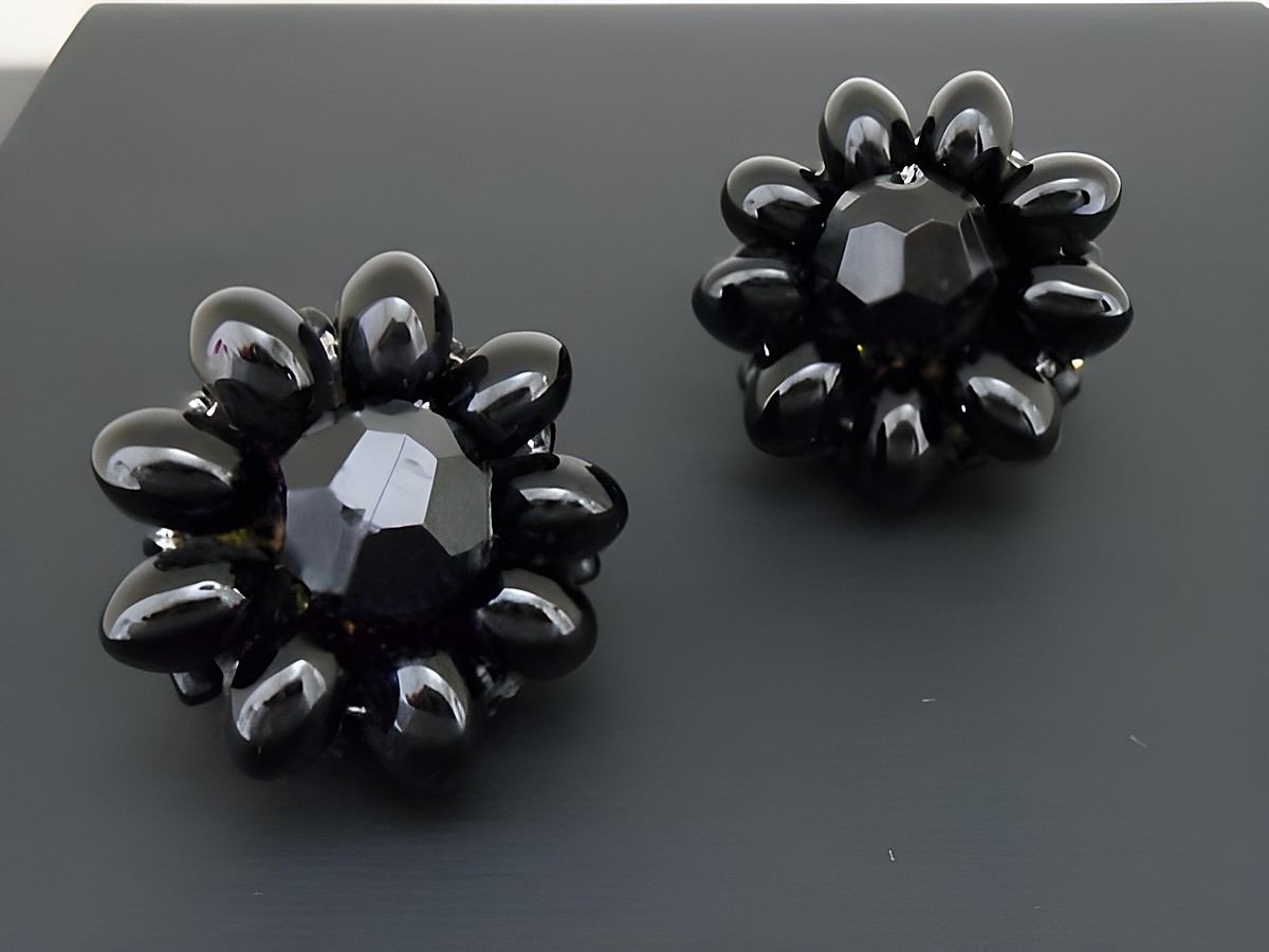 Ohrclip in schwarz mit blumigem Design und goldfarbenen Akzenten, verziert mit synthetischen Zuchtperlen, hergestellt von Juwelier Harnisch. Ideal für stilvolle Akzente.