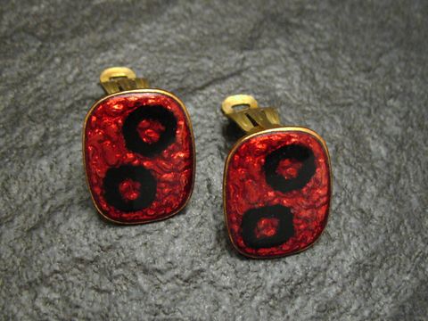 Ohrclips in rot-schwarz aus Emaille, vergoldet, im Vintage-Stil, hergestellt von Juwelier Harnisch, markantes Design mit kreisförmigen Mustern.