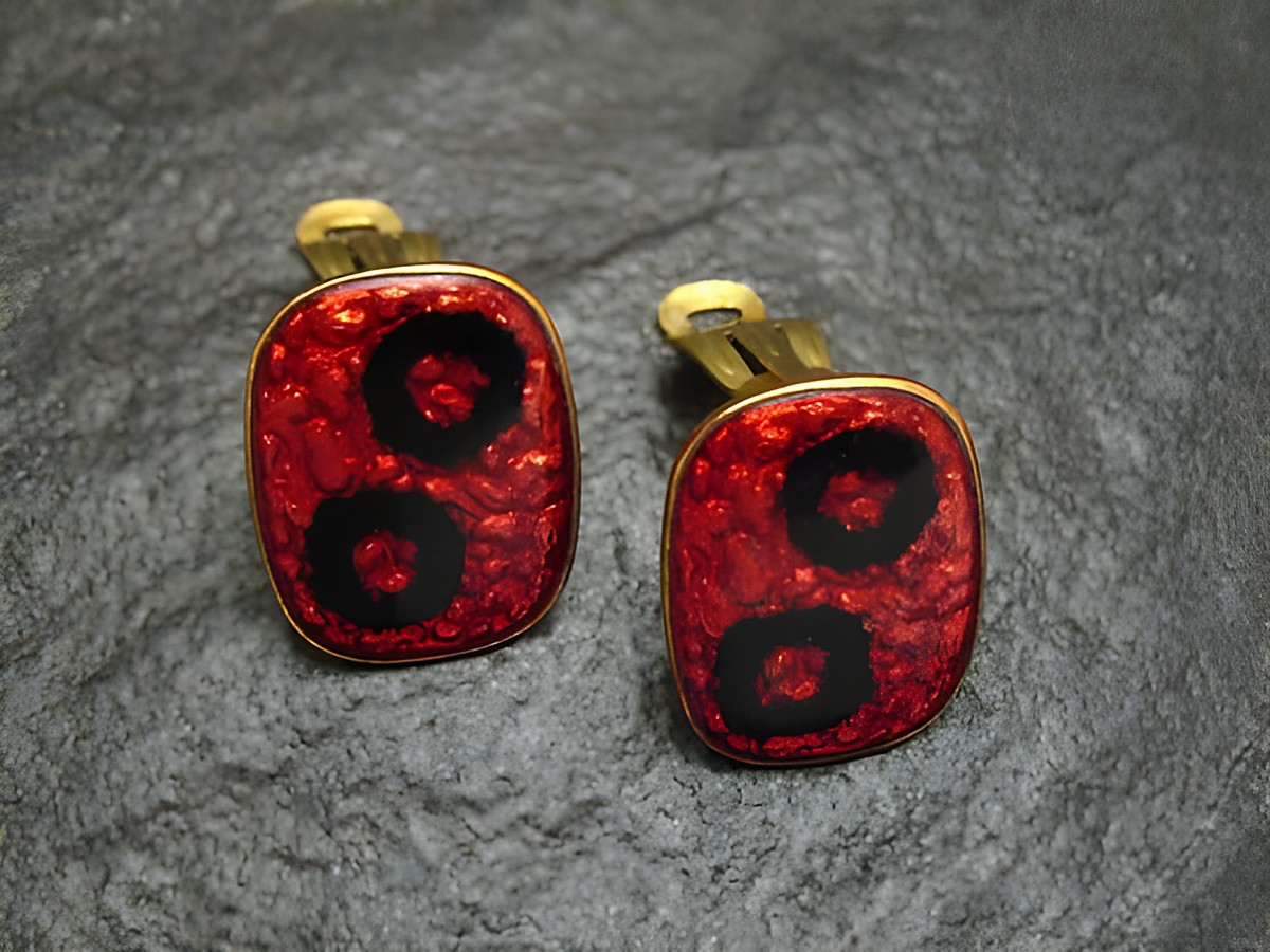 Ohrclips in rot-schwarz aus Emaille, vergoldet, im Vintage-Stil, hergestellt von Juwelier Harnisch, markantes Design mit kreisförmigen Mustern.
