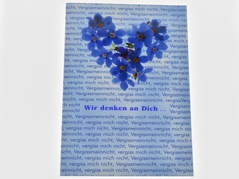 Geburtstagskarte mit einem herzförmigen Arrangement von blauen Vergissmeinnicht-Blumen auf einem Hintergrund mit dem Text Vergissmeinnicht in verschiedenen Schriftgrößen. Hersteller: Juwelier Harnisch.