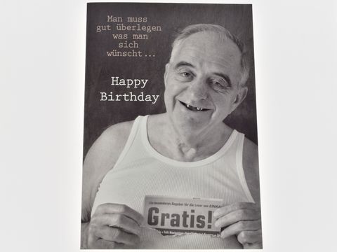 Eine humorvolle Geburtstagskarte zeigt einen älteren Herrn in einem weißen T-Shirt. Er lächelt und hält ein Schild mit der Aufschrift Gratis. Text oben enthält einen witzigen Spruch zum Geburtstag.