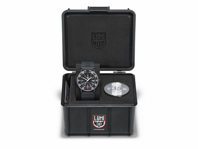 Die Luminox XS.3001.H.SET - NAVY SEAL Original Heritage Uhr in einer schwarzen Box, präsentiert mit Zubehör und einer runden zusätzlichen Platte. Zeitmesser mit markantem Design und robustem Look.