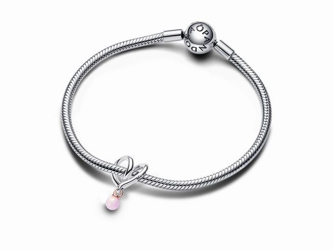 Bicolor eingehülltes Herz Charm von Pandora, aus Silber und roségold vergoldet, mit einer synthetischen opalen Kugel in Pink, befestigt an einem eleganten Armband.