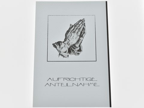 Trauerkarte mit betenden Händen in Schwarz-Weiß-Illustration, umrahmt von einem Rechteck. Darunter der Text "AUFRICHTIGE ANTEILNAHME" in eleganter Schrift. Hersteller: Juwelier Harnisch.