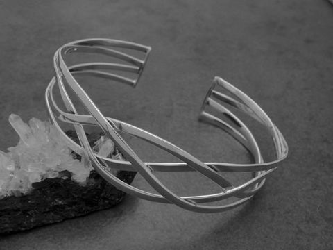 Silber Armreifen geflochten aus Sterling Silber mit einem Durchmesser von 19,5 mm und einer Länge von 19,3 cm, hergestellt von Juwelier Harnisch, elegant und modern, auf einer dunklen Unterlage.