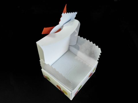 Geschenkschachtel für Baby-Taufe oder Geburt in Weiß mit bunten Figuren und einer orangenen Schleife, ideal zum Verschenken kleiner Aufmerksamkeiten, Hersteller Juwelier Harnisch.