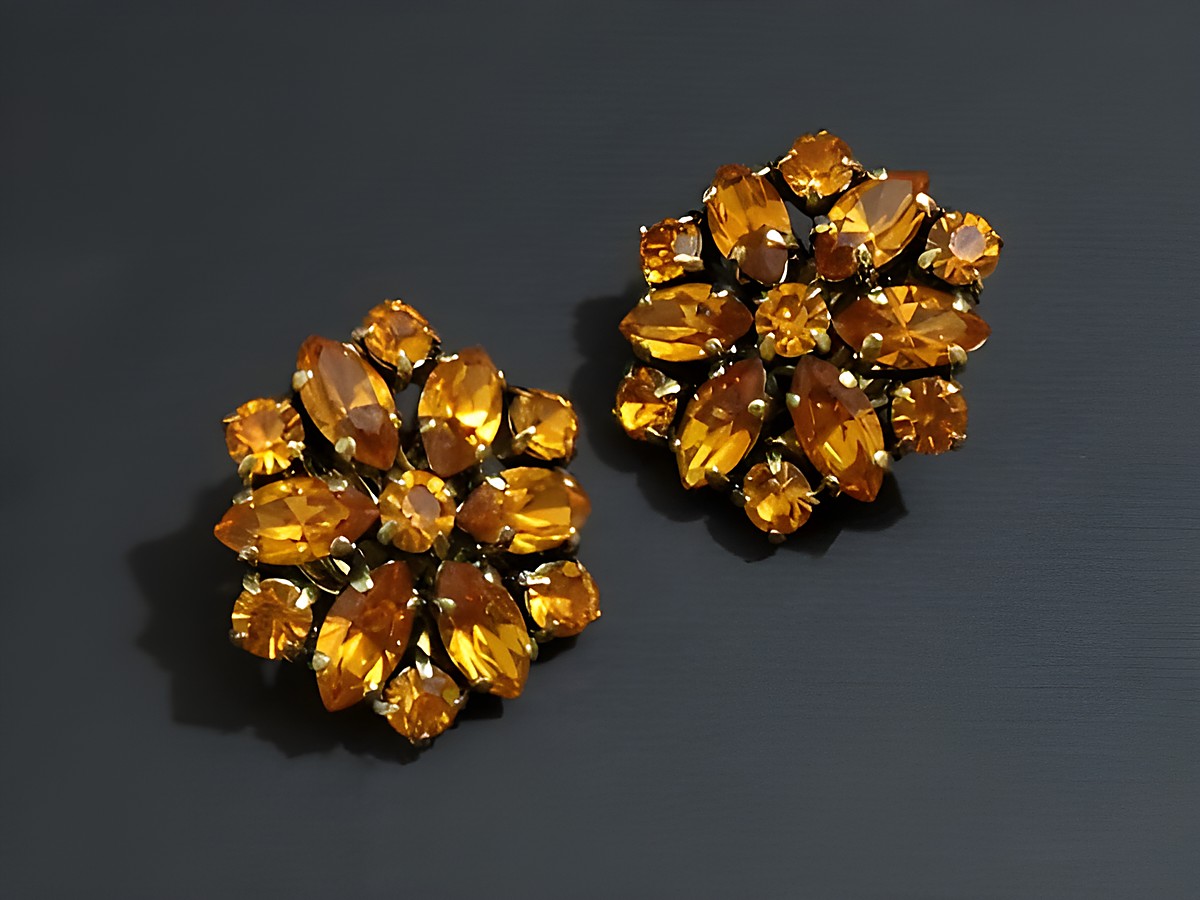 Strass Ohrclips prachtvoll in orange und goldfarben, hergestellt von Juwelier Harnisch, bestehen aus funkelnden, asymmetrisch angeordneten Schmucksteinen.