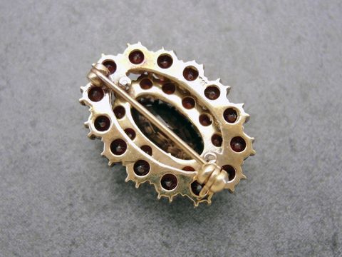 Oval geformte Granat Schmuck Brosche in Gold mit einer Größe von 29,2 mm, hergestellt von Juwelier Harnisch, verziert mit mehreren Granatsteinen.