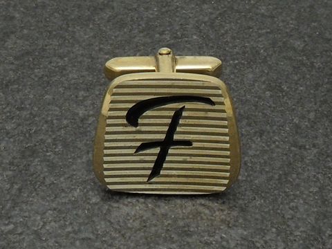Vergoldete Manschettenknöpfe mit den Initialen F, Hersteller Juwelier Harnisch, elegant gestaltete Oberfläche mit Rillenmuster und stilisiertem Buchstaben F.