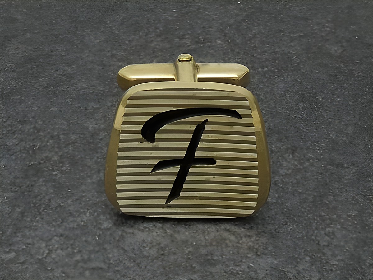 Vergoldete Manschettenknöpfe mit den Initialen F, Hersteller Juwelier Harnisch, elegant gestaltete Oberfläche mit Rillenmuster und stilisiertem Buchstaben F.