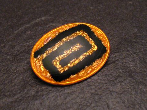 Emaille Brosche in ovaler Form mit gelbem Hintergrund und schwarzem geometrischem Muster, vergoldete Details, Vintage-Stück des Herstellers Juwelier Harnisch.