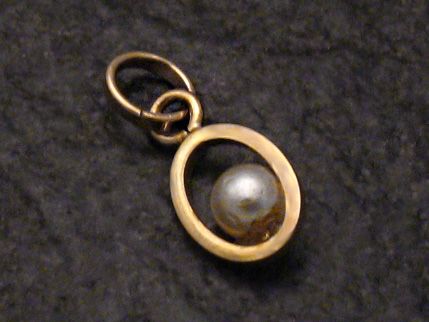 Anhänger mit unechter Perle in einem goldfarbenen Rahmen, gefertigt aus 333er Gold. Hersteller ist Juwelier Harnisch aus Seefahrt. Ein elegantes Schmuckstück für besondere Anlässe.