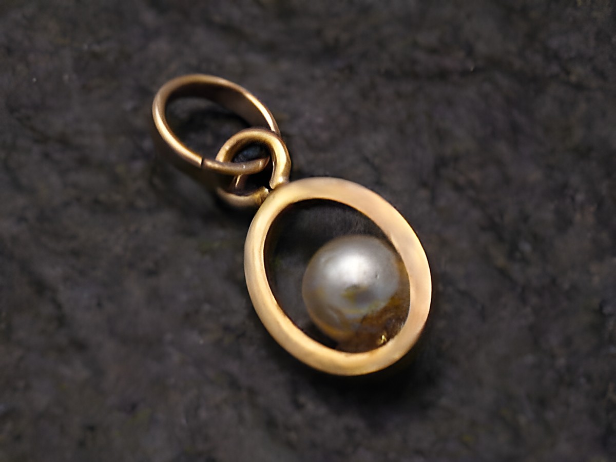 Anhänger mit unechter Perle in einem goldfarbenen Rahmen, gefertigt aus 333er Gold. Hersteller ist Juwelier Harnisch aus Seefahrt. Ein elegantes Schmuckstück für besondere Anlässe.