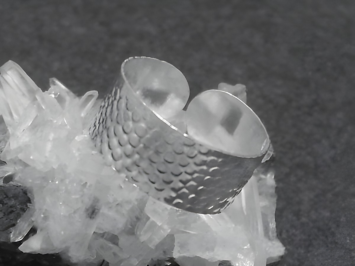 Silber Ring 8 mm breit mit Muster in Größe 55 bis 65, Hersteller Juwelier Harnisch, ohne Stein, auf Kristallbasis präsentiert.