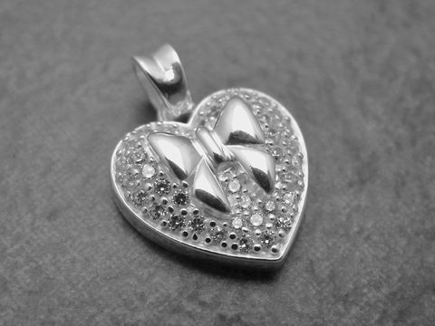 Herz mit Schleife aus Sterling Silber, verziert mit funkelnden Zirkonia, ideal als Anhänger. Hersteller: Juwelier Harnisch, Perlen & Steine.