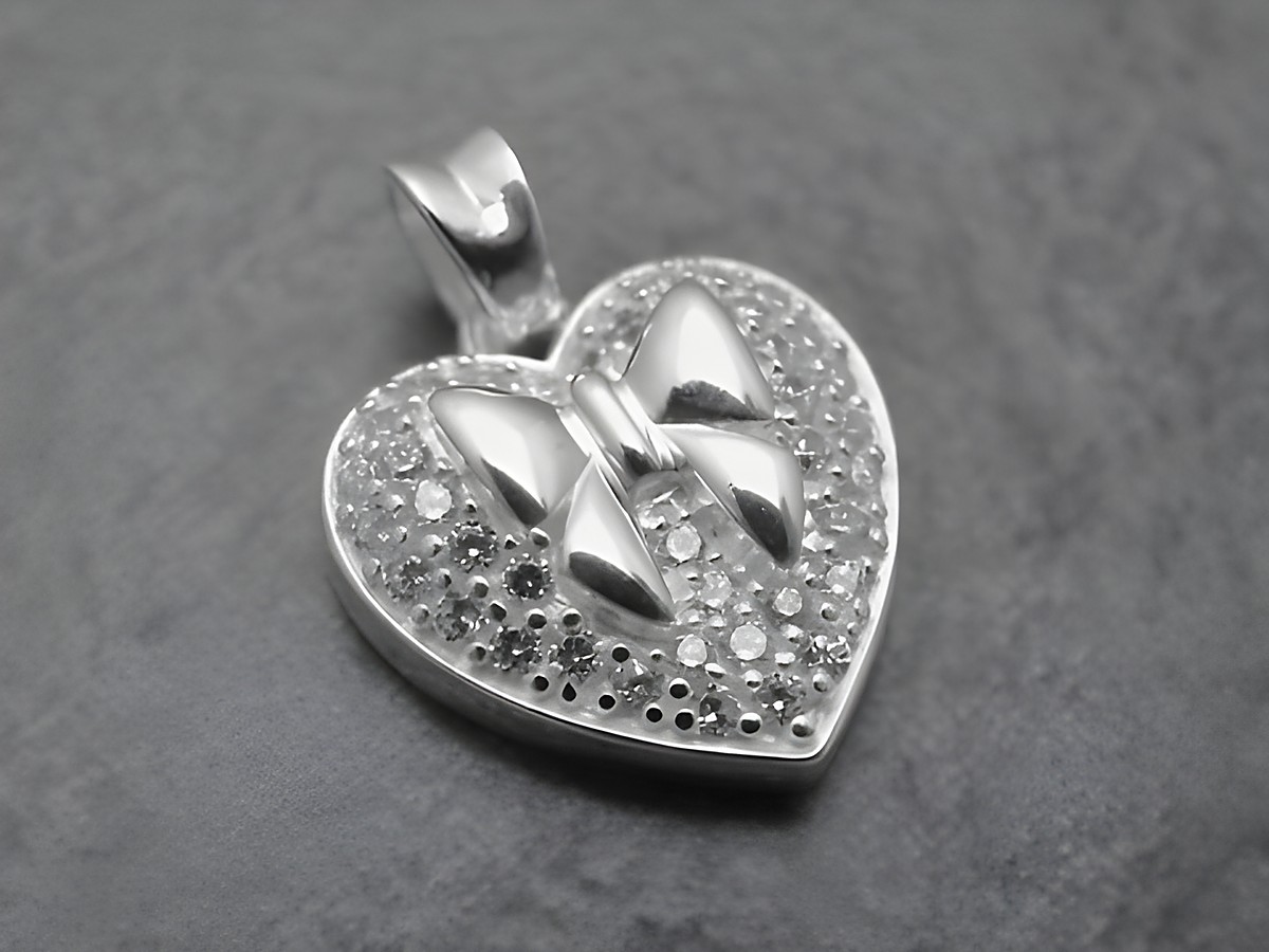 Herz mit Schleife aus Sterling Silber, verziert mit funkelnden Zirkonia, ideal als Anhänger. Hersteller: Juwelier Harnisch, Perlen & Steine.