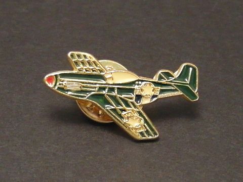 Segelflugzeug grün Pin Anstecker Anstecknadel des Herstellers Juwelier Harnisch, Darstellung eines stilisierten Flugzeugs mit goldenen Details und roter Nasenspitze auf dunklem Hintergrund.