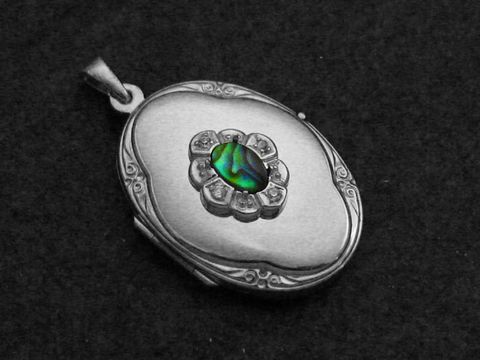 Paua Shell Medaillon Cabochon in rhodiniertem Sterling Silber, gefertigt von Juwelier Harnisch, mit kunstvoller Verzierung und schimmerndem, grünem Farbenspiel im Inneren.